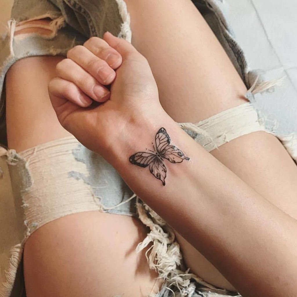Tatuaje minimalista de mariposa en la muñeca